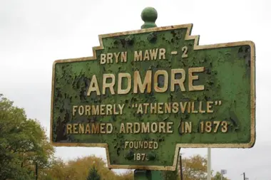 A historic Ardmore sign along a tree-lined street.